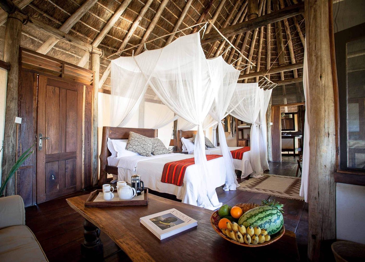 Baldachine Betten unter reetgedecktem Dach, mit frischen Früchten in Apoka Safari Lodge
