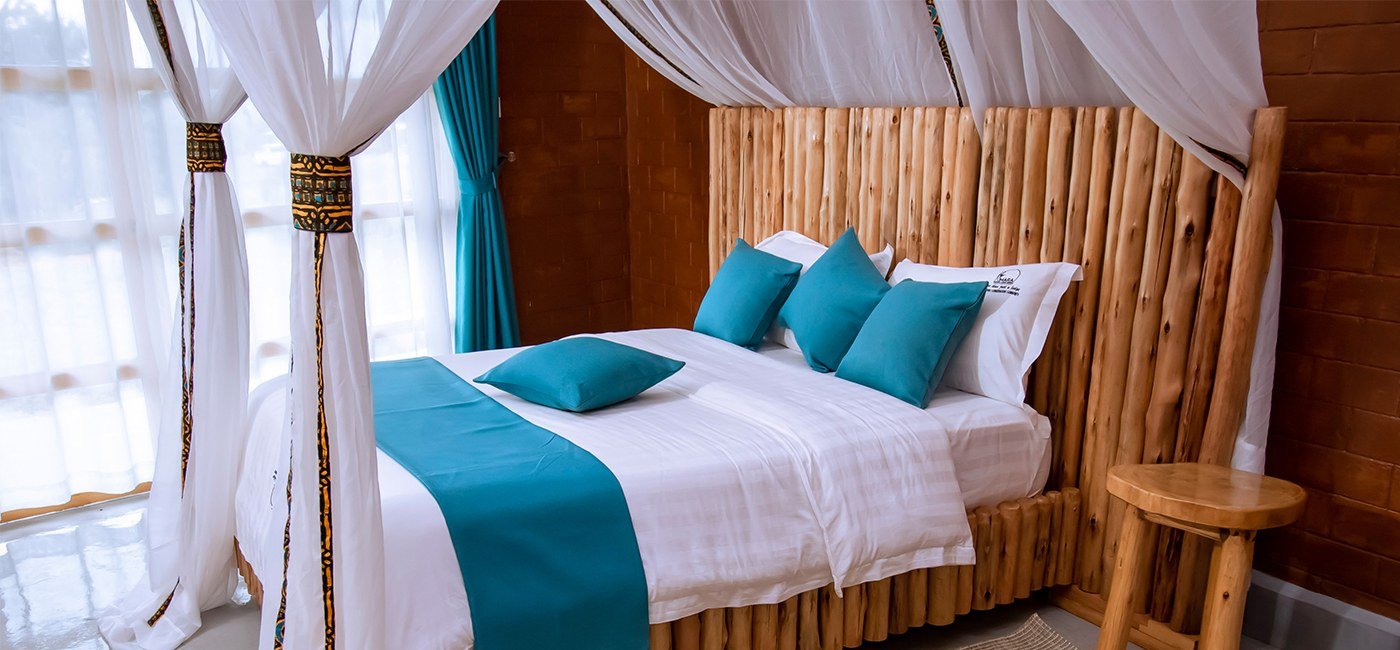 Un lit à baldaquin avec des oreillers bleu-vert à Mara Safari Lodge Kidepo
